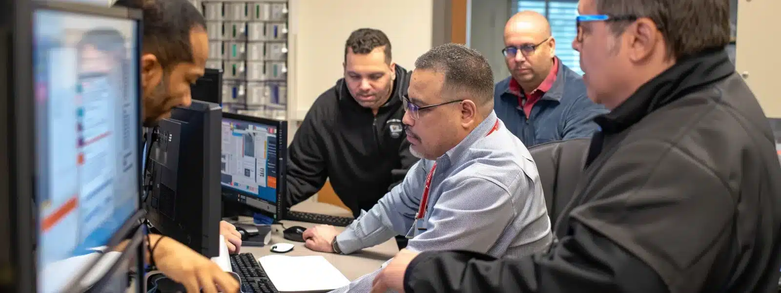 a group of employees collaborating around a computer, updating policies and procedures while showcasing a culture of continuous improvement and cybersecurity awareness.