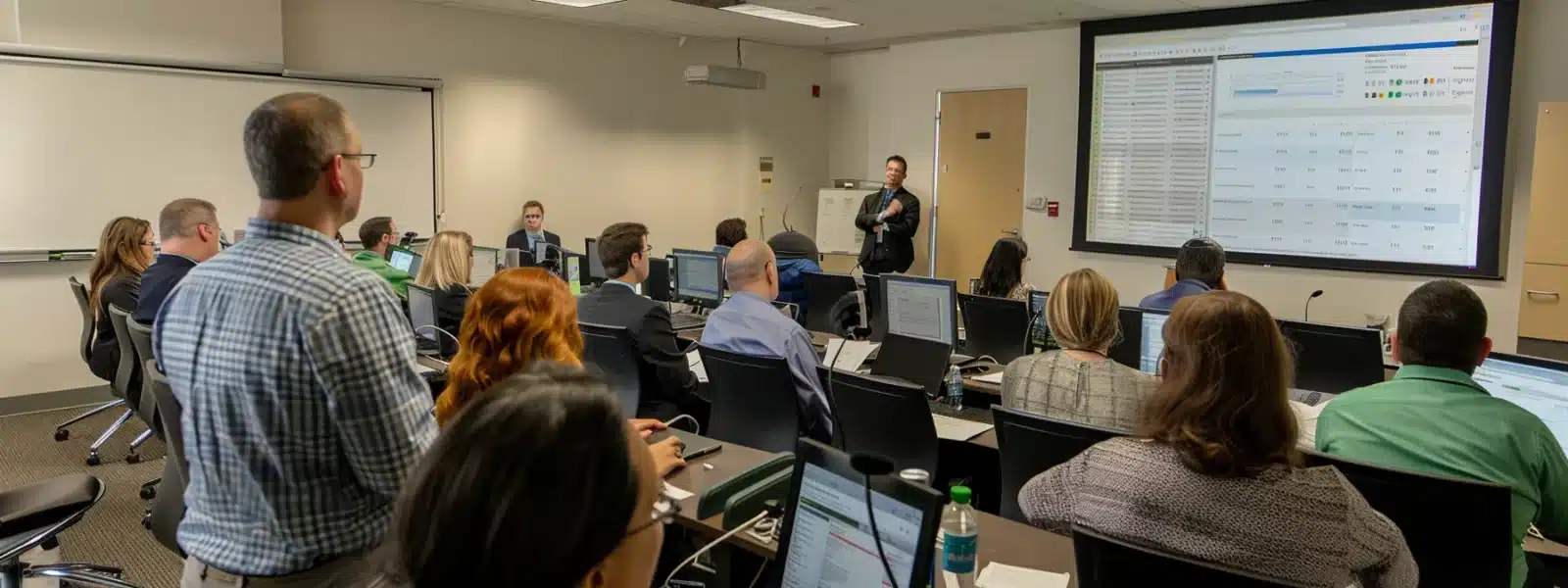 a team of cybersecurity professionals monitor screens displaying real-time compliance data, while attending a training session on updated cmmc requirements.